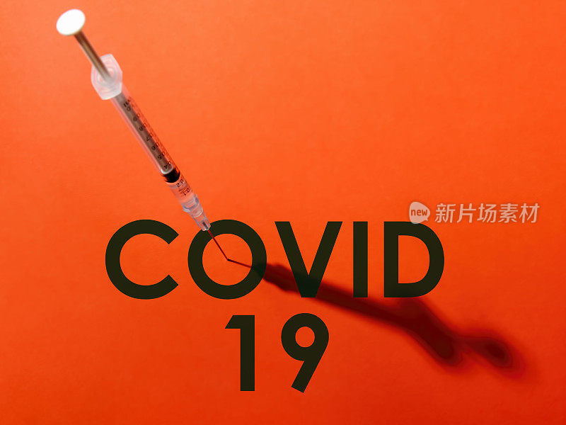 注射器上的针头穿过单词COVID-19 (COVID-19)中的字母“o”的中心。